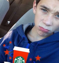 a young man sitting in the back seat of a car holding a cup of coffee