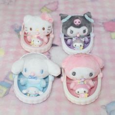 four hello kitty toys sitting on top of a pink table cloth covered in white and blue material