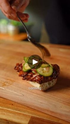 someone cutting up some food on top of a wooden board with a knife and fork