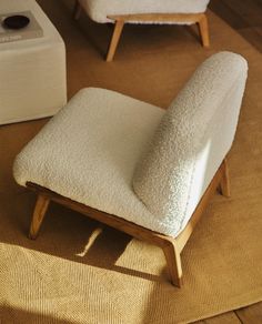 a white chair sitting on top of a wooden floor next to a footstool