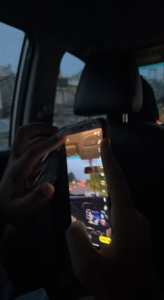 someone is using their cell phone while in the back seat of a car at night