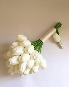 a bouquet of white tulips is held up against the wall by a wooden handle