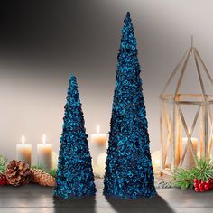 two blue christmas trees sitting next to each other with lit candles in front of them