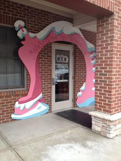 an entrance to a building with a pink and blue mural on it's side