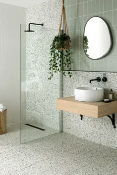 a bathroom with a sink, mirror and plants in the shower stall next to it