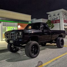 a large black truck parked in front of a store