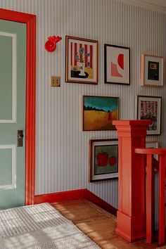 a room with pictures on the wall and a red table in front of an open door