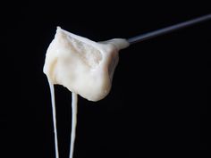 marshmallows being dipped with toothpicks on a black background