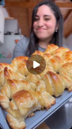 a woman is smiling while holding a tray with baked goods on it and the video appears to be being viewed