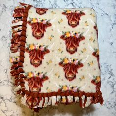 a close up of a blanket on a counter with flowers and tassels around the edges