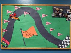 a car race made out of paper on a bulletin board with cars driving down the track