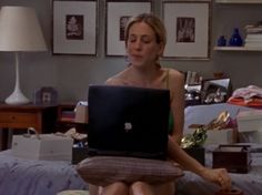 a woman sitting on a bed using a laptop computer