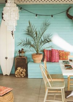 a room with a table, chairs and a surfboard on the wall