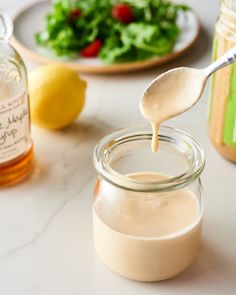 a spoon full of mayonnaise next to a plate with salad