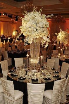 a tall vase filled with white flowers sitting on top of a black and white table