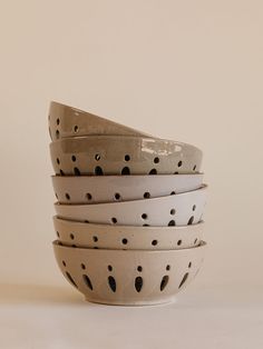 a stack of white and black bowls sitting on top of each other in front of a beige wall