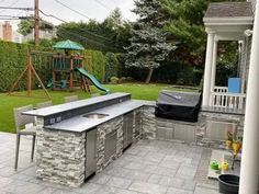 an outdoor kitchen with grill and slide in the back yard