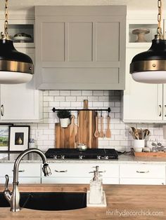 two lights hanging over a kitchen counter top next to a sink and stovetop oven