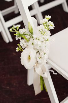 a bouquet of flowers sitting on top of a white chair next to another chair with chairs in the background