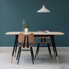 a dining room table with two chairs and a vase on the table next to it