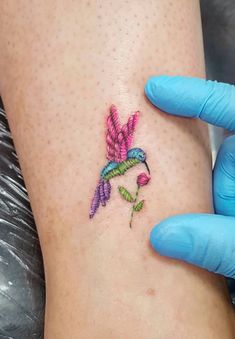 a small tattoo on the leg of a woman's foot with a bird and flower