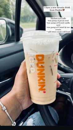 a person holding up a drink in their hand with the words dunkin'on it