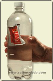 a hand holding a plastic bottle filled with water and an energy bar in it's wrapper