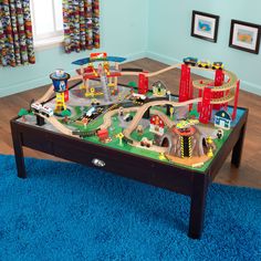 a child's toy train set on a coffee table in a room with blue carpet