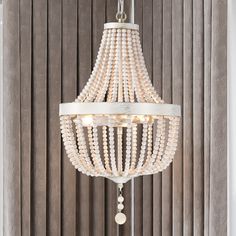 a white chandelier hanging from the ceiling in a room with wooden slats