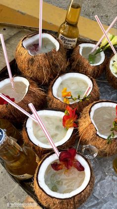 there are many coconuts on the table with drinks in them and straws sticking out of them