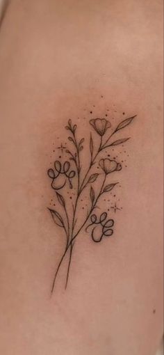 the back of a woman's shoulder with flowers and leaves tattooed on her left side