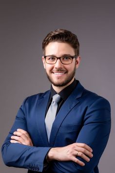 a man in a blue suit and tie with his arms crossed