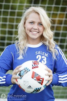 a woman holding a soccer ball in front of a net