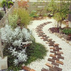 a garden path made out of wooden planks and gravel in front of a fence