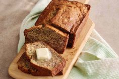 sliced loaf of banana bread on a cutting board next to a green towel and butter