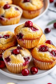 several cranberry muffins on a white plate with cherries around them