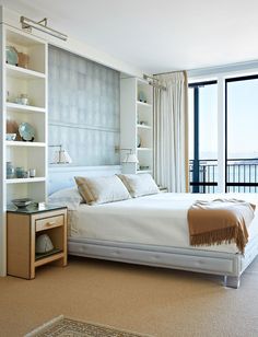 a white bed sitting next to a window in a bedroom