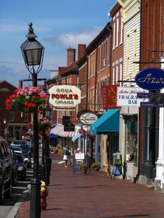 a street lined with shops and parked cars next to tall brick buildings on both sides