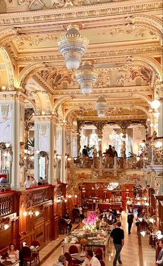 an ornately decorated dining room with chandeliers and people eating at tables in it