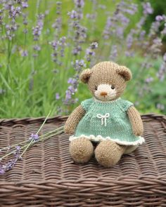 a small teddy bear sitting on top of a wicker basket next to lavender flowers