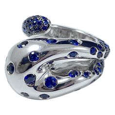 de GRISOGONO blue sapphire serpent openwork cocktail ring in 18kt white gold, circa 2000. Designed in the shape of an abstract openwork snake coiled around the finger, this ring’s domed head is flush-set throughout with circular-cut royal blue sapphires, the tail pave-set throughout with similarly-cut deep blue sapphires. Sapphires: circular-shape; estimated 3.5 carats in total; royal blue color (assessed). Signed "de GRISOGONO”; maker’s mark for de GRISOGONO; numbered "B 32415”; stamped "53” fo Serpent Snake, Maker’s Mark, Royal Blue Color, White Ring, Cocktail Rings, White Gold Rings, Deep Blue, Blue Sapphire, Sapphire Ring