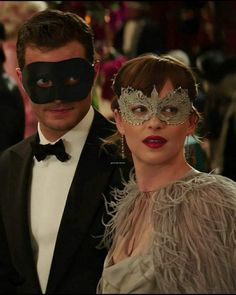 a man and woman wearing masks standing next to each other