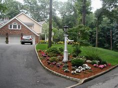 a car parked in front of a house next to a driveway with flowers and trees