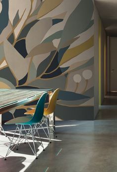 a dining room table and chairs in front of a wall with abstract designs on it