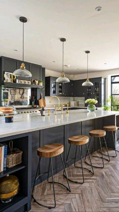 a kitchen with black cabinets and white counter tops, along with bar stools in front of the island