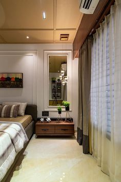 a bed room with a neatly made bed next to a mirror and window sill