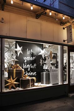 a store front with christmas decorations and presents in it's display window at night