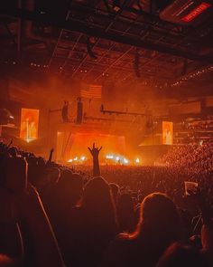 an audience at a concert with their hands up in the air and lights shining down on them