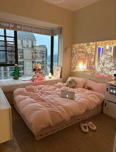 a bed with a laptop on top of it in a room next to a window