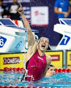 a woman in a pink swimsuit is holding her arm up as she dives into the water